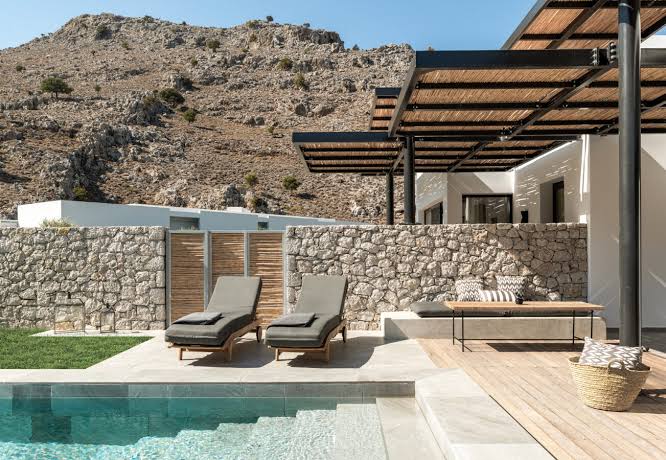 Stepped white blocks with timber shading around a long pool and rough planting